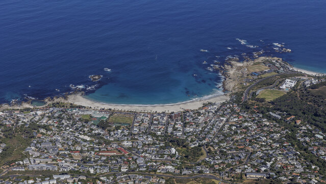 Aerial view of where turquoise waters meet sandy shores and sprawling urban development, Cape Town, Western Cape, South Africa.