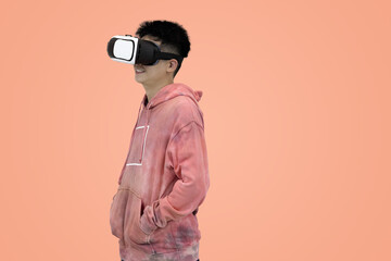 Excited young Asian man wear hoodie reacting with joy while wearing a virtual reality headset, symbolizing the thrilling first experience in studio background