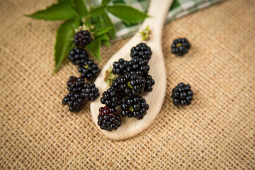 Black blackberries on wooden spoon in rustic style
