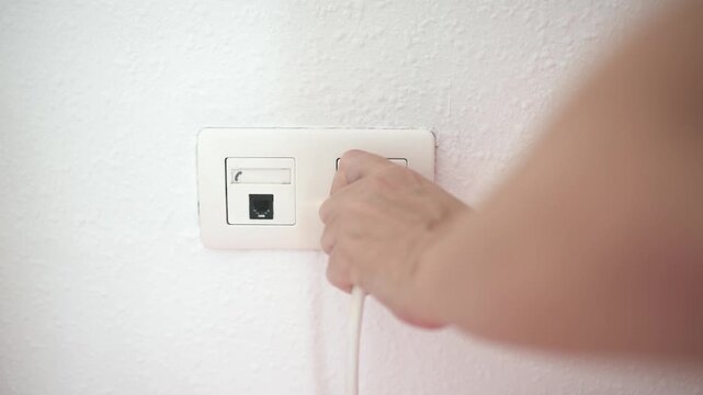 Man hand plug in charger adapter into wall socket close up
