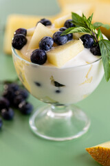 Dessert parfait of yogurt melon and blueberries on a green background