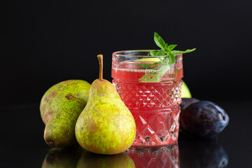 Bright fruit drink for a diet with pears and plums on a black background © Peredniankina