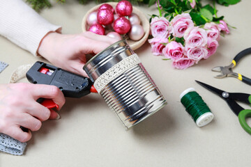 Florist at work: woman shows how to make modern Christmas decoration with fir, roses, pink baubles and decorative stars. The base is classic can. Step by step, complete tutorial.