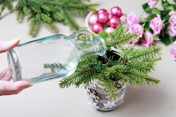 Florist at work: woman shows how to make modern Christmas decoration with fir, roses, pink baubles and decorative stars. The base is classic can. Step by step, complete tutorial.