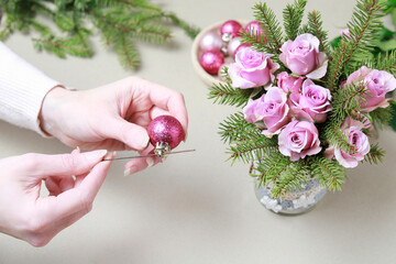 Florist at work: woman shows how to make modern Christmas decoration with fir, roses, pink baubles and decorative stars. The base is classic can. Step by step, complete tutorial.