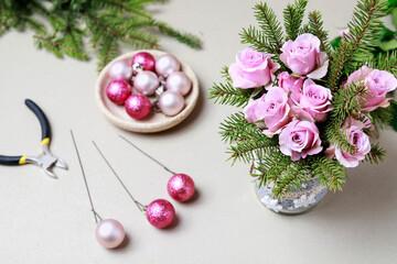 Florist at work: woman shows how to make modern Christmas decoration with fir, roses, pink baubles and decorative stars. The base is classic can. Step by step, complete tutorial.