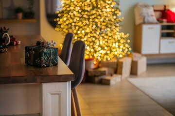 Warm Christmas setting with decorated table, wrapped gifts, and blurry festive lights. Cozy holiday background