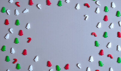 Christmas frame, candy shapes arranged as a festive border on a gray background. Gentle, childlike holiday layout perfect for overlays, cards, crafts, seasonal visuals. Copy space. Flat lay, top view