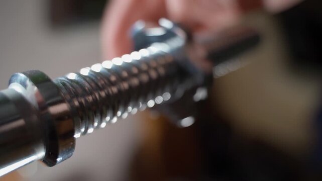 The barbell is spinning on a large thread of the rod, close-up. Unscrewing the rod nut on a blurred background