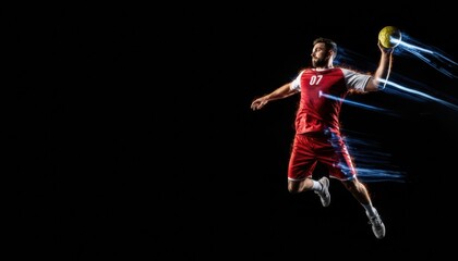 Male handball player in red uniform jumping to throw the ball with dynamic blue light trails creating a sense of motion and power on a black background with copy space