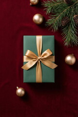 Christmas or New Year background with gift box and fir branch decorations on red velvet backdrop. empty copy space for text.holiday and celebration concept for postcard or invitation. top view