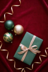 Christmas or New Year background with gift box and fir branch decorations on red velvet backdrop. empty copy space for text.holiday and celebration concept for postcard or invitation. top view
