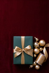 Christmas or New Year background with gift box and fir branch decorations on red velvet backdrop. empty copy space for text.holiday and celebration concept for postcard or invitation. top view