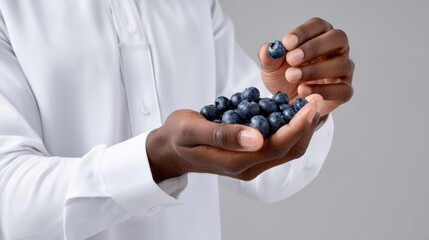 A man is holding a bunch of blueberries in his hand. Concept of freshness and health, as blueberries are known for their nutritional benefits