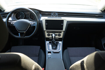 Detailed close up view of modern car interior. Front panel with steering wheel, shift lever and dashboard. Interior of the modern car. Cockpit with exclusive decoration