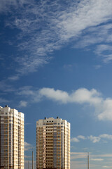 Urban residential architecture with multi storey apartment buildings and lampposts lighted with evening sun under blue sky with light clouds and copy space vertical shot.