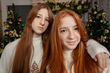 Two young women with long red hair wearing white Christmas sweaters