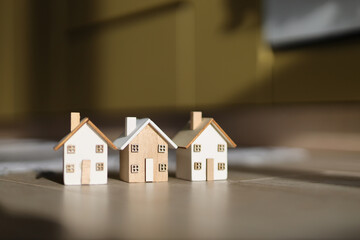 Miniature wooden houses on floor with sunlight shadows