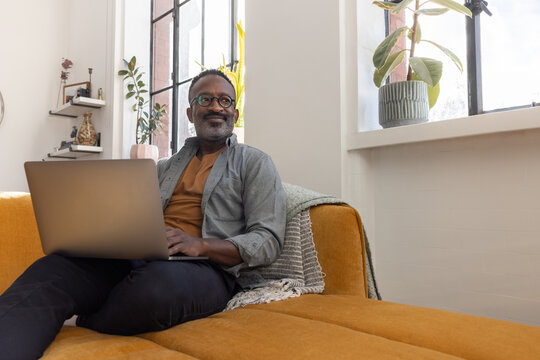 Happy Man Enjoying Working from home with Laptop in Natural Light