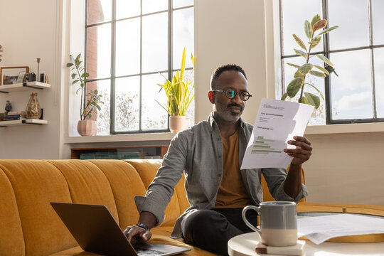 Mature man looking at paperwork and using a laptop computer to pay energy bills