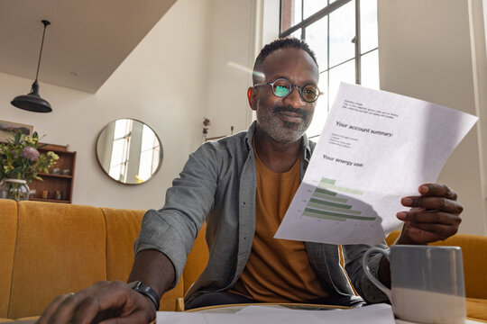 Smiling man enjoys reviewing energy usage summary document