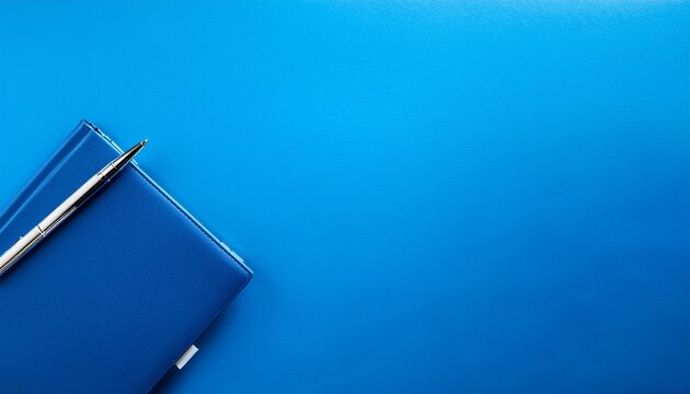 blue notebook and steel pen on a vibrant blue surface minimalist background with copy space