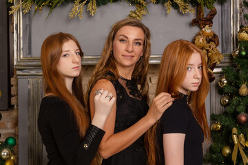 A family portrait featuring a mother and her two daughters, who have long red hair