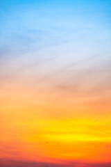 Sunset or sunrise sky with a vibrant gradient of orange, gold, and soft blue. Clear atmosphere with wispy clouds. Peaceful, natural light background. hope, freedom, new day Concepts, Vertical