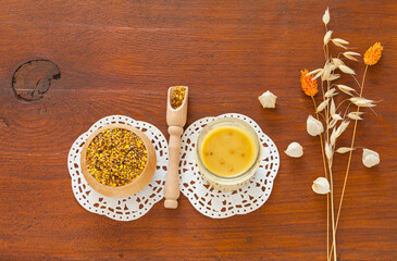 Healhy beekeeping product – grains of fermented flowers pollen in wooden bowl and jar of mixed honey on wooden table. Pollen grains are natural food supplement and source of oll vitamins. Copy space
