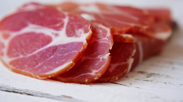 Close-up of thinly sliced cured meat on a distressed white surface. Focus on the red and white textures