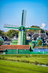 Beautiful traditional Dutch windmill painted in green, set against a vibrant blue sky.