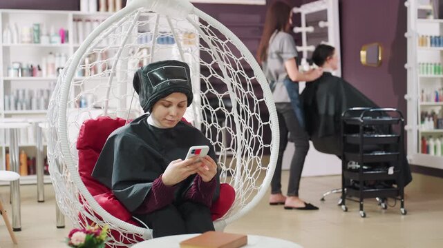 calm client in hanging chair, client unwinds while stylist prepares another appointment, tranquil scene where client lounge in hanging seat as stylist gets ready for next appointment