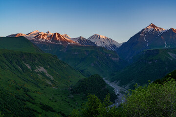 Evening light on snowy Caucasus peaks above winding river valley