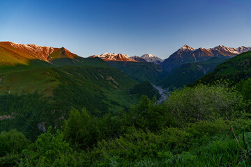 Evening light on snowy Caucasus peaks above winding river valley