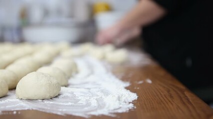 A female baker forms dough balls for buns. Macro photography.