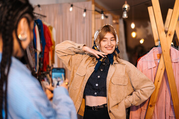 Stylish Young Woman Posing in Trendy Clothing Store with Friend Capturing Moment