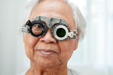 Asian senior woman wearing ophthalmic vision eye test and using optical trial frame.