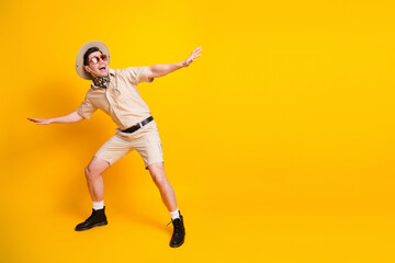 Adventure seeker in tropical safari outfit posing playfully against bright yellow background