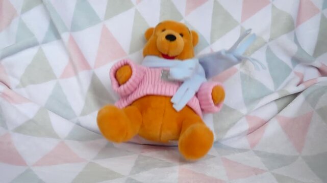 Slow motion shot of Winnie the Pooh teddy bear falling on colorful blanket