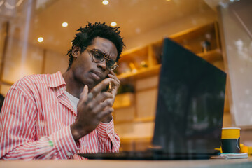 Focused man using laptop and smartphone simultaneously in café. Symbolic of digital workflow, tech‑driven productivity and remote connectivity in everyday modern work life.