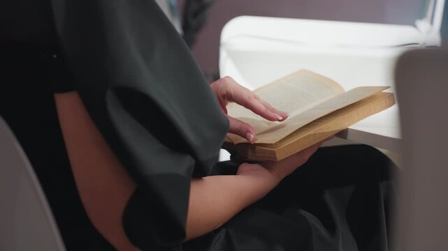 tranquil woman enjoying book, serene lady peacefully engaged in her favorite book at beauty salon, calm female patron sitting comfortably and reading her novel while awaiting services in salon