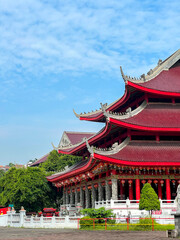 Obraz premium An exterior view of the Sam Poo Kong temple roof in Semarang, Central Java, featuring a tiered structure, red tiles, and curved eaves. This traditional Chinese building is set against a bright blue