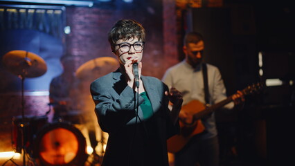 Artistic lady singing microphone at dark modern stage closeup. Beautiful woman