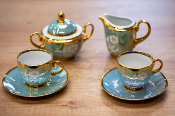 Porcelain tea set with two cups, saucers, sugar bowl and creamer in blue and gold. Classic shapes with artistic detailing, hinting at vintage and historic design.