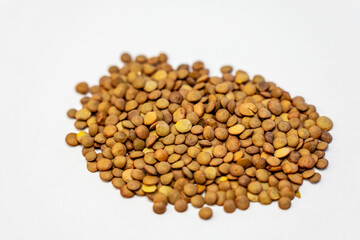 Pile of dry brown lentils on a white background. Clean food ingredient photo ideal for packaging, product listings, recipes and healthy nutrition content.