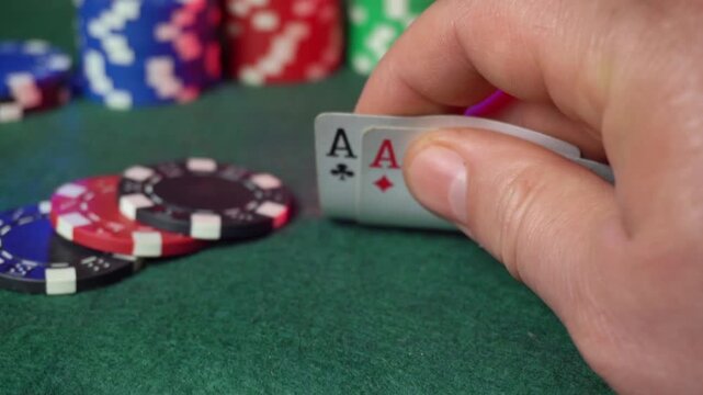 A hand grips an ace card while playing poker on a green felt table. Surrounding colorful chips indicate a competitive atmosphere, capturing the excitement of the game.