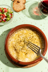 Grilled provolone cheese seasoned with oregano on green background.