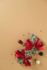 Two stylish wrapped Christmas gifts on a clean beige vertical background