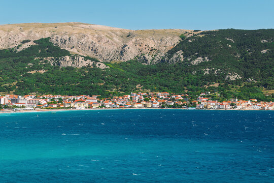Picturesque coastal town with vibrant blue sea and mountainous background. Baška, Krk island, Croatia - Powered by Adobe