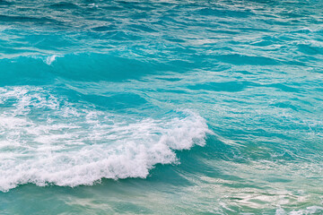 Vibrant turquoise ocean waves crashing onto sandy shoreline